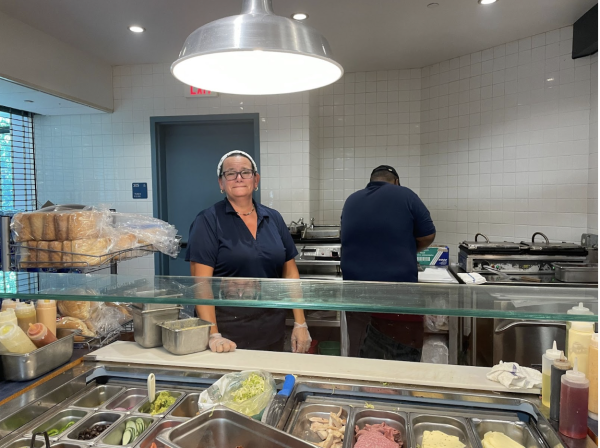 Staples cafeteria staff member Amber Egervari poses in front of the new four panini presses provided for the sandwich line. 